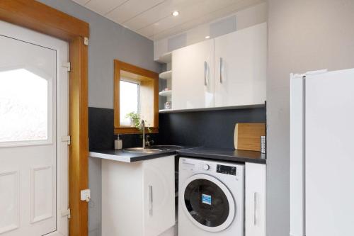 a kitchen with a washing machine and a sink at Lomond Serviced Apartments- Inglewood in Alloa