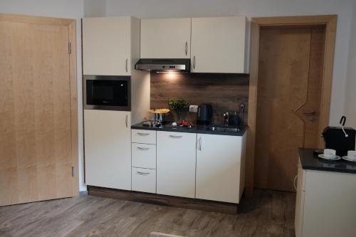 a small kitchen with white cabinets and a microwave at Apart Felsenhof in Längenfeld