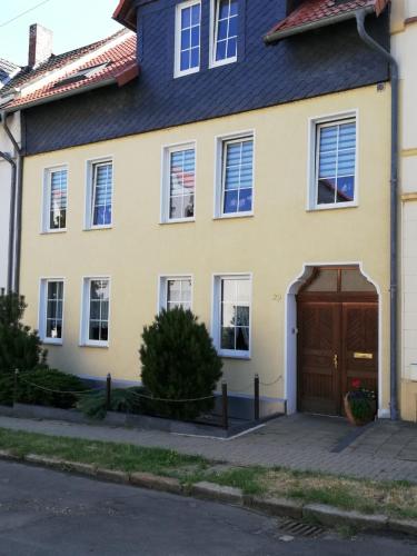une maison jaune avec une porte brune dans l'établissement Ferienwohnung Mephisto und Faust, à Thale