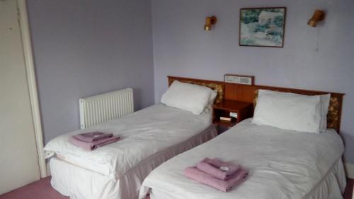 two beds in a room with pink towels on them at Neuadd Arms Hotel in Llanwrtyd Wells