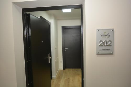 a hallway with a black door and a sign at Apart Hotel Family in Sarajevo