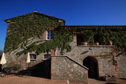 a building covered in ivy with tables and chairs at Agriturismo La Sovana in Sarteano
