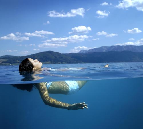 a woman is floating in the water at Haus Gruber in Attersee am Attersee