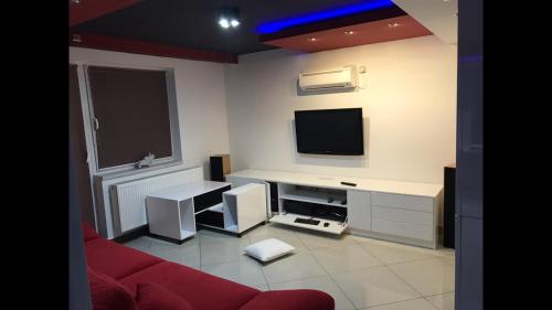 a living room with a red couch and a flat screen tv at Korona Panzió in Balog nad Ipľom