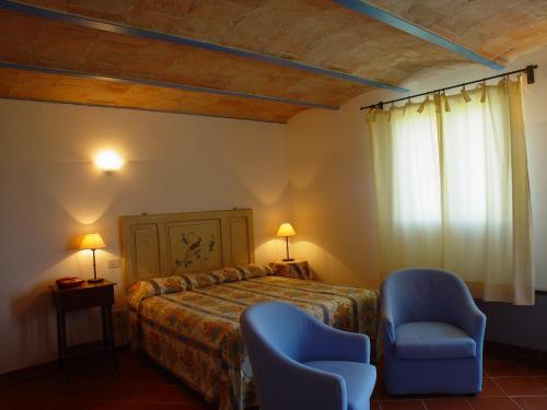 a bedroom with a bed and two blue chairs at Agriturismo La Sovana in Sarteano