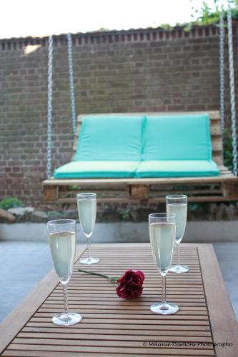 - une table avec trois verres à vin et une rose dans l'établissement Comme à la maison - BASILIQUE, à Saint-Quentin
