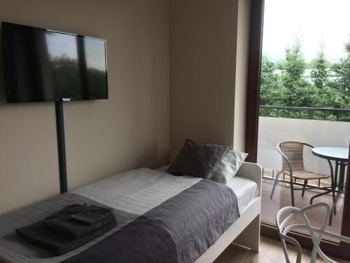 a bedroom with a bed with a flat screen tv on the wall at Apartament Fibra Latte in Rybnik