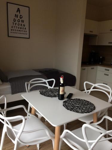a white table and chairs with a bottle on it at Apartament Fibra Latte in Rybnik