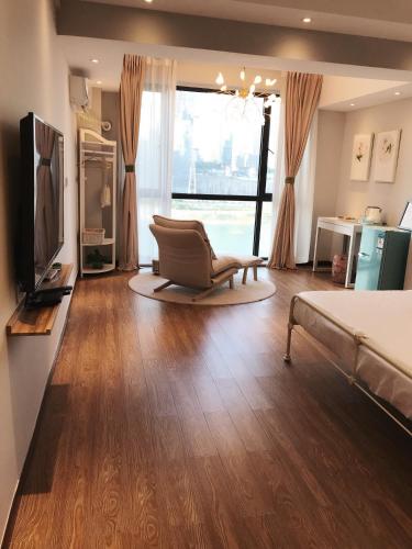 a bedroom with a bed and a chair and a television at Chongqing Ouranjian Lake View Guesthouse in Chongqing