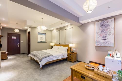 a bedroom with a large bed and a table at Chongqing Ouranjian Lake View Guesthouse in Chongqing