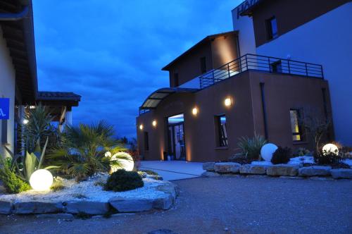 uma casa com luzes de lado à noite em The Originals City, Hôtel des Arts, Montauban (Inter-Hotel) em Nègrepelisse