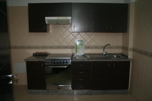 - une cuisine avec des placards noirs, une cuisinière et un évier dans l'établissement Appartement de Mustapha larache, à Larache