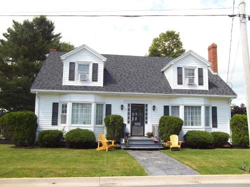 a white house with yellow chairs in the yard at Abide Within Bed & Breakfast in Truro