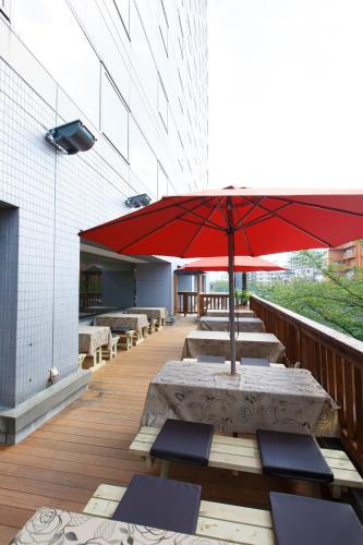 a row of tables with a red umbrella on a balcony at Day Nice Hotel Tokyo in Tokyo