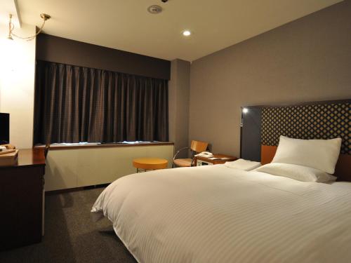 a bedroom with a large white bed and a window at Mito Keisei Hotel in Mito
