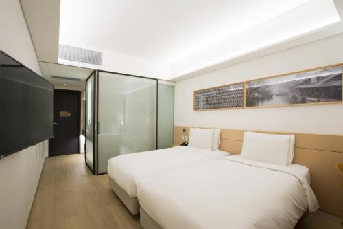 a bedroom with a large white bed and a tv at Sotetsu Hotels The Splaisir Seoul Myeongdong in Seoul