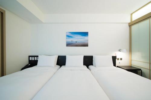 a bedroom with two beds and a painting on the wall at Sotetsu Hotels The Splaisir Seoul Myeongdong in Seoul