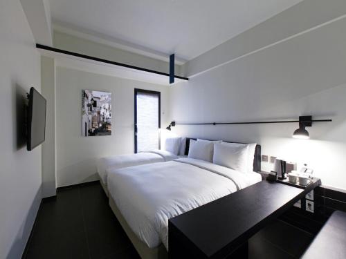 a white bedroom with two beds and a desk at Sotetsu Hotels The Splaisir Seoul Myeongdong in Seoul