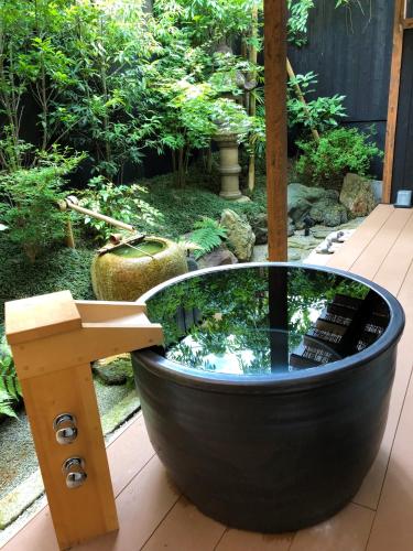 a bath tub with a pond in a garden at Kamishichiken Oku in Kyoto