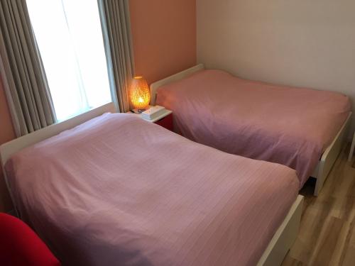 two beds in a room with a lamp and a window at Business Hotel La Firenze in Tokyo
