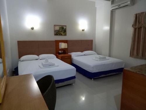 Cette chambre comprend 2 lits et une table. dans l'établissement Asia Novo Boutique Hotel - Rosario, à Rosario