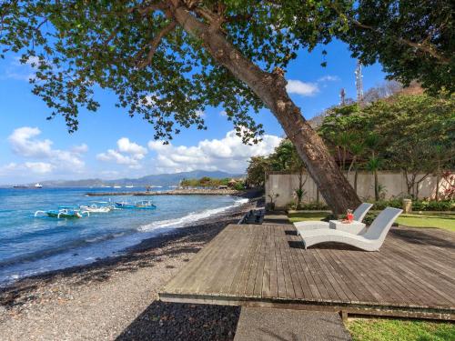 a group of chairs sitting on a table next to the water at Villa Pantai Candidasa by Villa Finder in Candidasa