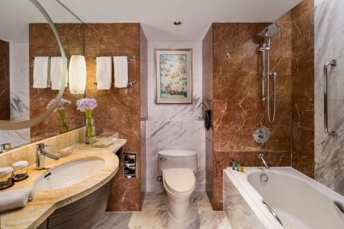 a bathroom with a tub and a toilet and a sink at The Kunlun Jing An in Shanghai