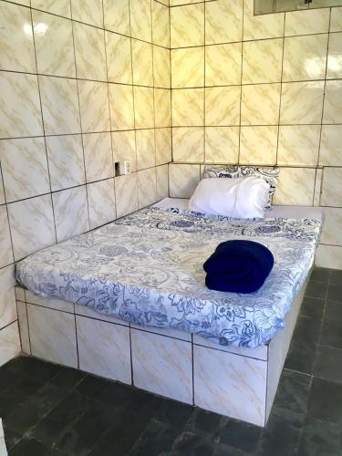 a bed with a blue hat on top of it at Kitnet BH in Belo Horizonte