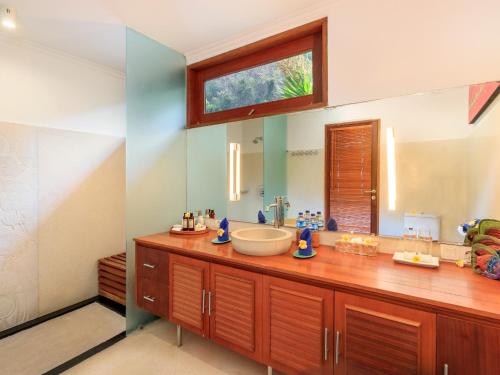 a bathroom with a sink and a large mirror at Villa Pantai Candidasa in Candidasa
