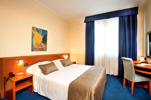 a hotel room with a bed and a desk and a window at Best Western Blu Hotel Roma in Rome