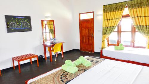 a bedroom with a bed and a table and a desk at Regina Beach Bungalow in Trincomalee