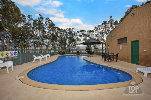 a pool on a patio with chairs and tables at Lake Fyans Holiday Park in Lake Fyans