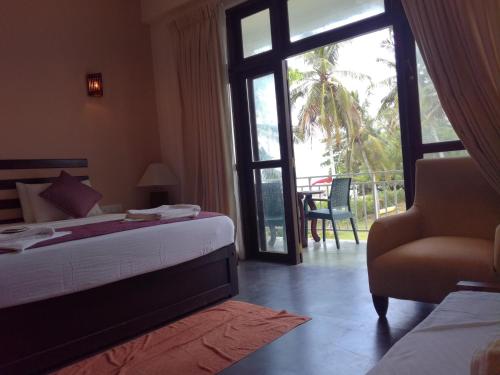 a bedroom with a bed and a chair and a window at Seacoast Sanctuary Beach Hotel in Hiriketiya