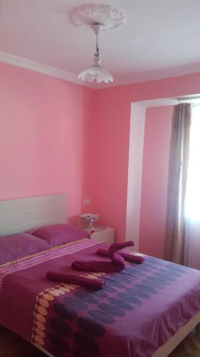 - une chambre avec des murs roses et un lit avec des draps violets dans l'établissement Hermosa Vista, à Tbilissi