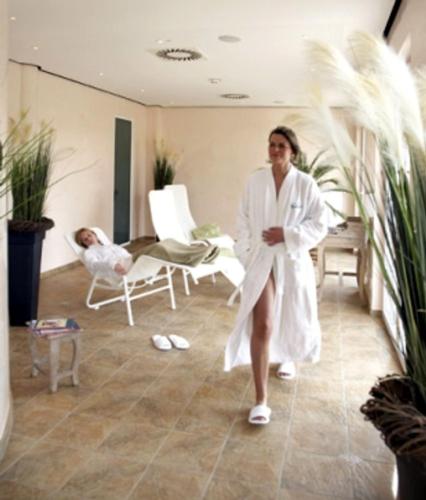 a woman in a robe standing in a room with a child in chairs at Waldhotel Nachtigall in Paderborn