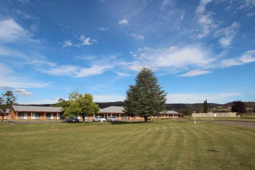 a large yard with a tree in front of a building at Bushman's Motor Inn in Lithgow