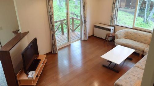 a living room with a couch and a television at Cottage Ginkai Fuji in Yamanakako