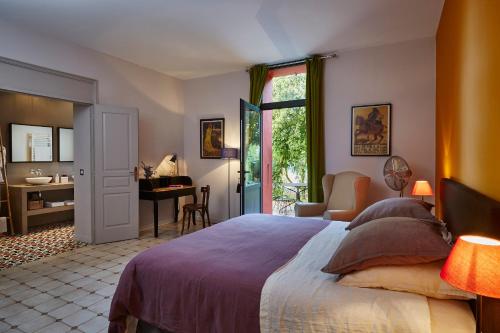 a bedroom with a large bed with a desk and a chair at Clos Des Aspres in Ortaffa