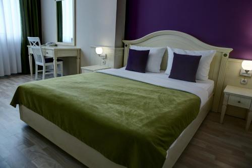 a bedroom with a large bed with purple walls at Hotel Gorenje in Pristina
