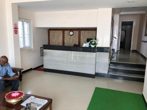 a man sitting on a couch in a lobby at Hotel GARISHPARK in Rāmanāthapuram