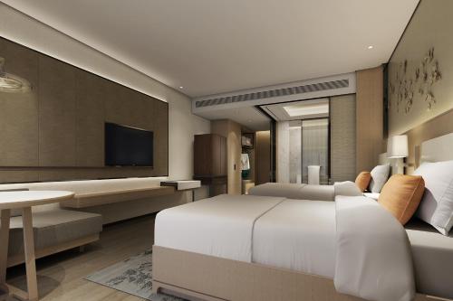 a bedroom with a large white bed and a tv at Howard Johnson Zhujiang Hotel Chongqing in Chongqing