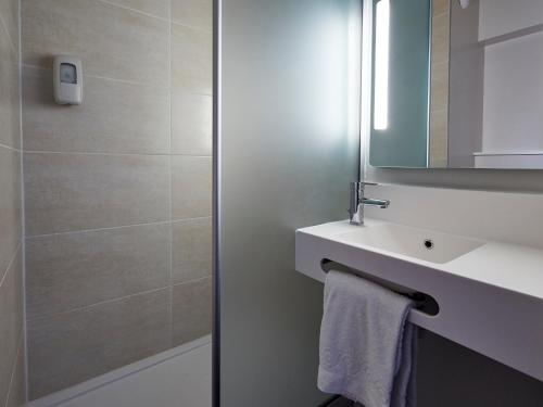 ein Bad mit einem Waschbecken und einem Spiegel in der Unterkunft B&B HOTEL Orleans Saint-Jean de Braye in Saint-Jean-de-Braye