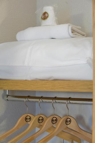 a wooden shelf with hangers next to a bed at B&B HOTEL Orleans Saint-Jean de Braye in Saint-Jean-de-Braye