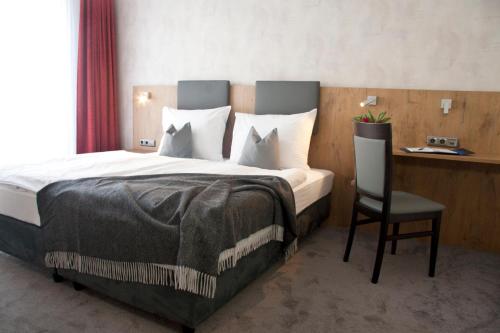 ein Schlafzimmer mit einem großen Bett und einem Stuhl in der Unterkunft Boardinghouse Landshut in Landshut