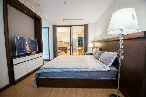 ハノイにあるHong Gia Tue Apartmentのベッドルーム(ベッド1台、テレビ、ランプ付)