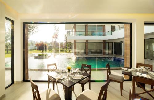 ein Esszimmer mit einem Tisch, Stühlen und einem Pool in der Unterkunft Saint Simeon Beach Residence in Long Hải