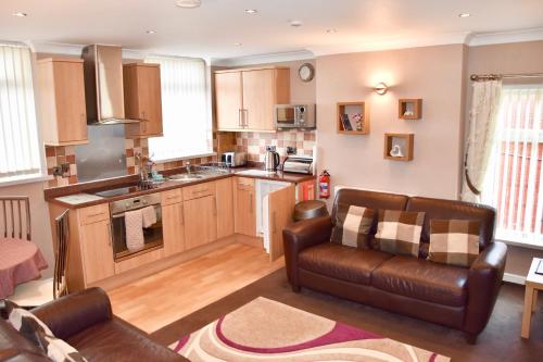 a living room with a couch and a kitchen at Empress Select Holiday Flats in Blackpool