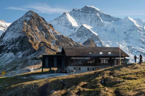 a building on a hill with mountains in the background at O 68 Haus Bel Air in Wengen