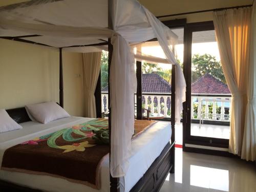 a bedroom with a canopy bed and a balcony at Mandhara Chico Bungalow in Lovina