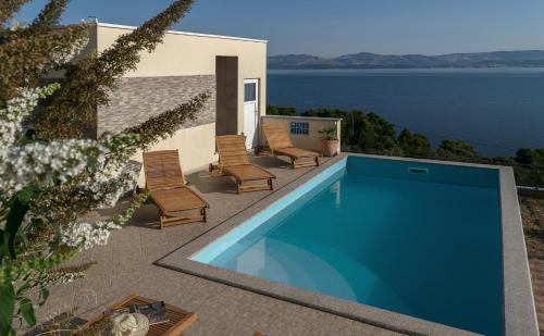 a swimming pool on a patio with chairs and the water at Vila Vita in Donje Selo na Šolti